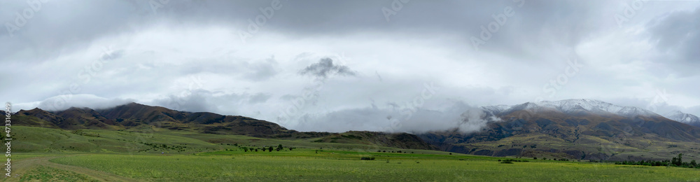 Clouds lying on the tops of snow-capped mountains in the Altai mountains