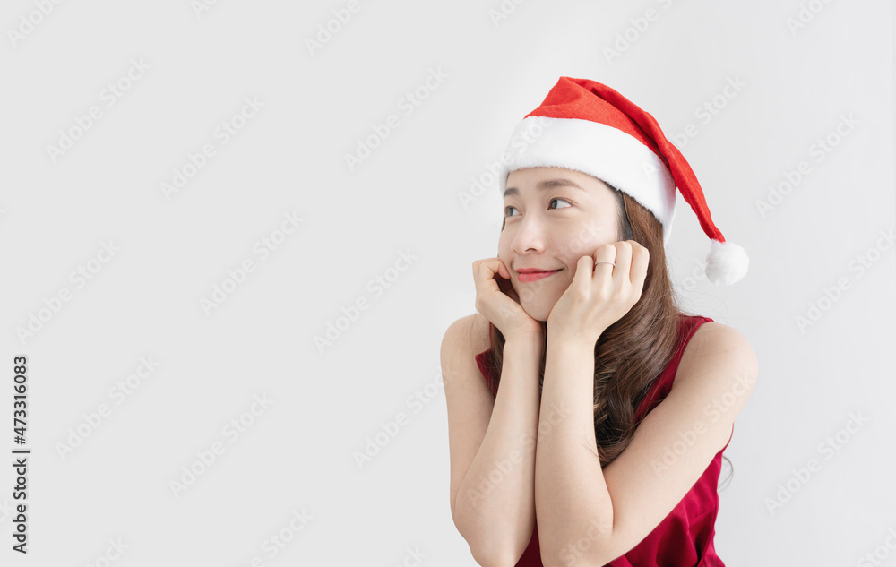 Asian woman wearing santa hat and red dress, with smiling face looking at copy space Asian woman wearing santa hat and red dress, with smiling face looking at copy space