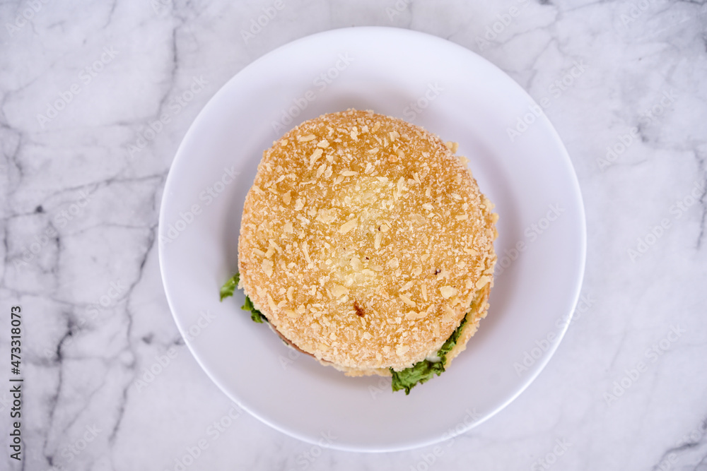 Simple beef burger with ham and lettuce are served on a white plate. Bakery, Fast food concept. Street food concept. Simple beef burger with ham and lettuce are served on a white plate. Bakery, Fast food concept. Street food concept.