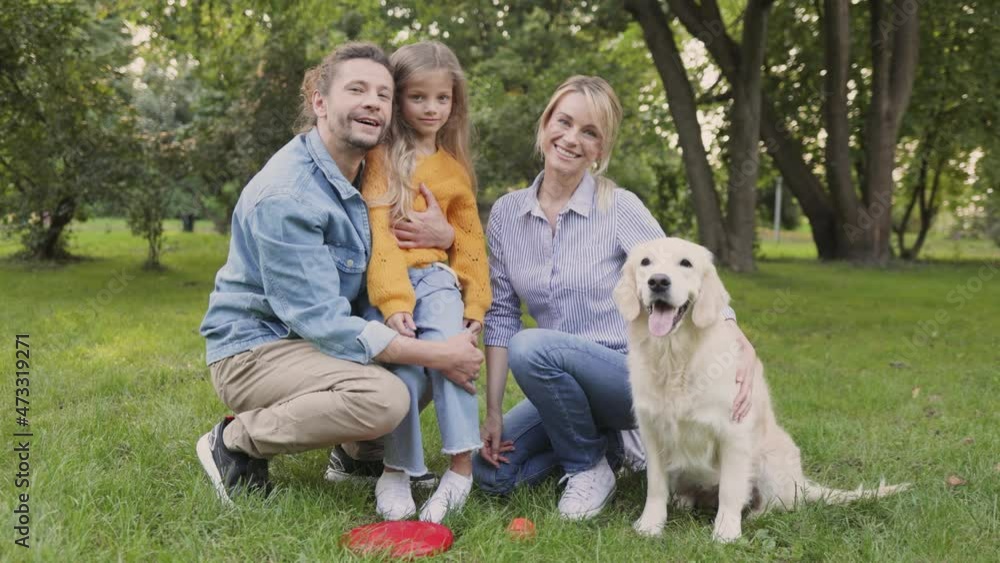 Overjoyed family carry cute retriever while walking in park. Portrait of happy people sitting in park with cute dog while enjoying warm summer day together Overjoyed family carry cute retriever while walking in park. Portrait of happy people sitting in park with cute dog while enjoying warm summer day together