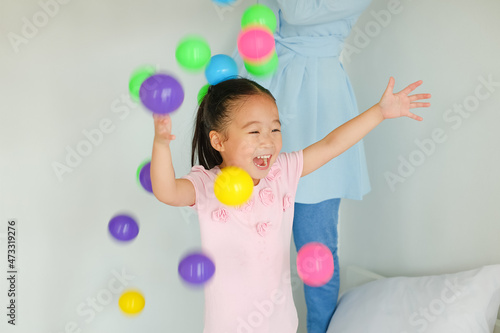 Asia family playing colorful ball on bed
