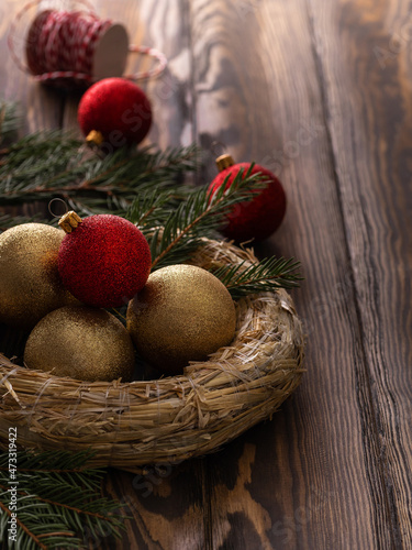 Christmas handmade decoration, diy wreath on wooden rustic table. Selective focus. Red and golden balls, festive sustainable preparation.