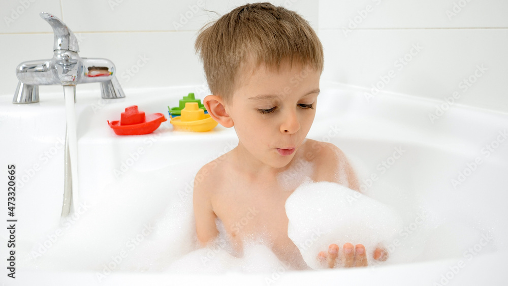 Happy smiling boy having bath and playing with soap foam. Concept of hygine, children development and fun at home Happy smiling boy having bath and playing with soap foam. Concept of hygine, children development and fun at home