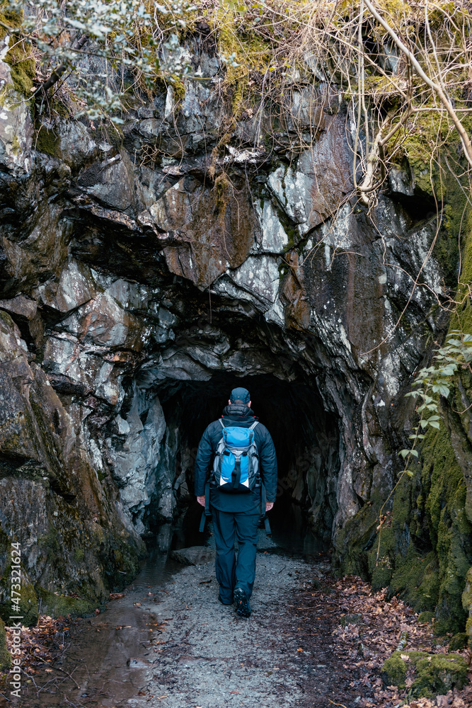 Person with a rucksack walking into a cave