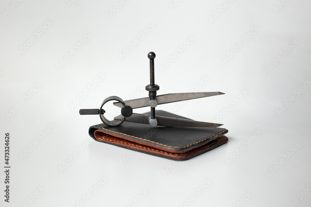 Leather wallet brown and black on a white background with leatherworking tools, leather goods Leather wallet brown and black on a white background with leatherworking tools, leather goods