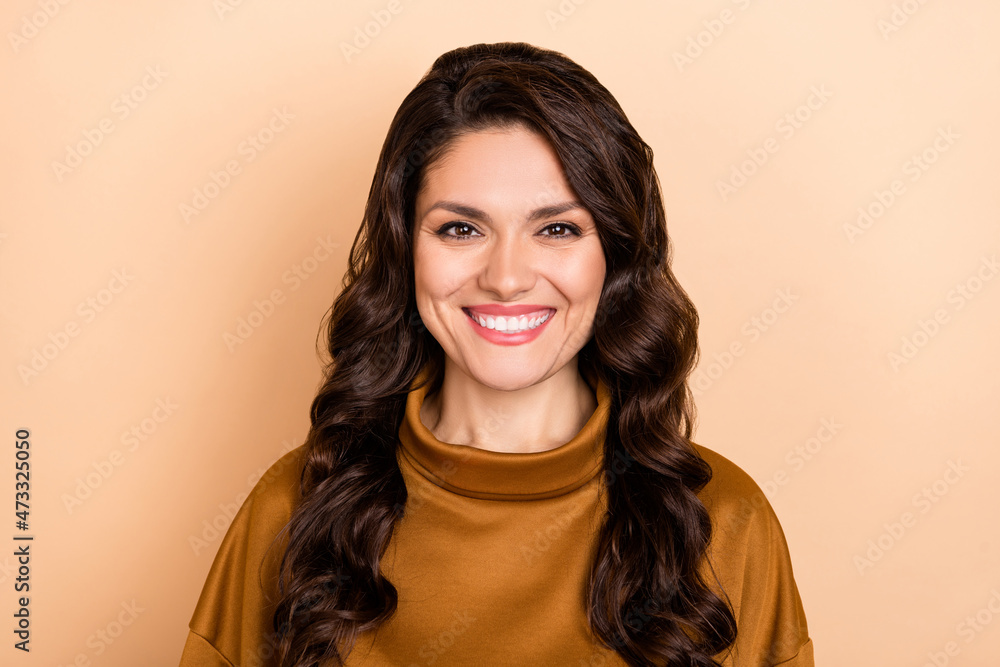 Portrait of attractive content cheerful wavy-haired woman beaming smile isolated over beige pastel color background Portrait of attractive content cheerful wavy-haired woman beaming smile isolated over beige pastel color background