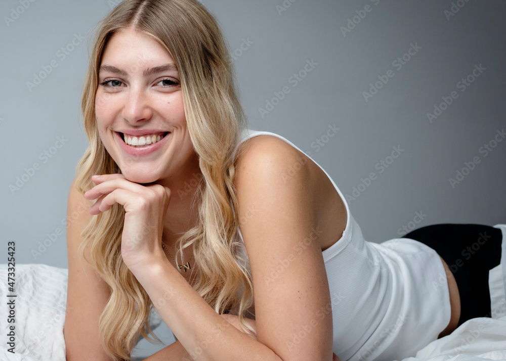 Beautiful blond woman with hand on chin lying on bed at home