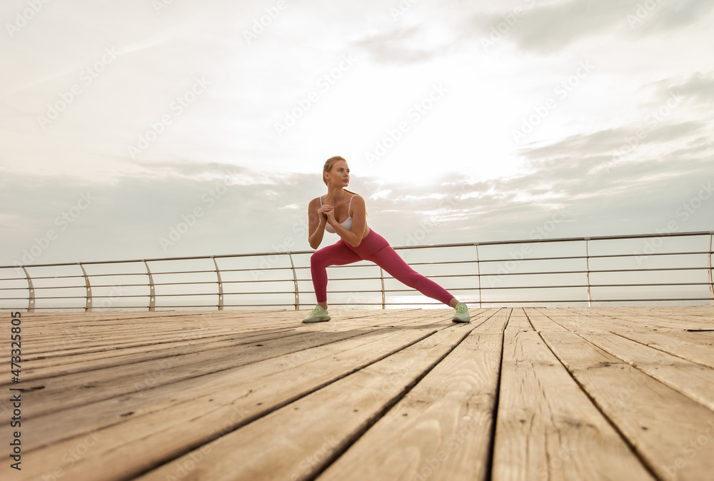 Young woman doing fitness, aerobics workout on the beach in the early morning Young woman doing fitness, aerobics workout on the beach in the early morning