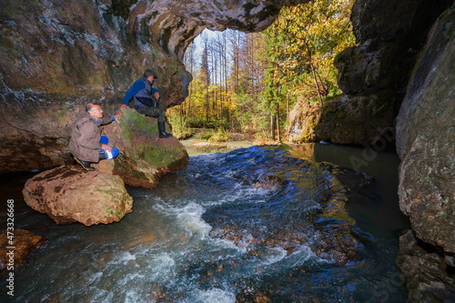 mature tourists-cavers explore the grotto in the atysh karst cave and the stream flowing from it. Bashkortostan. photo