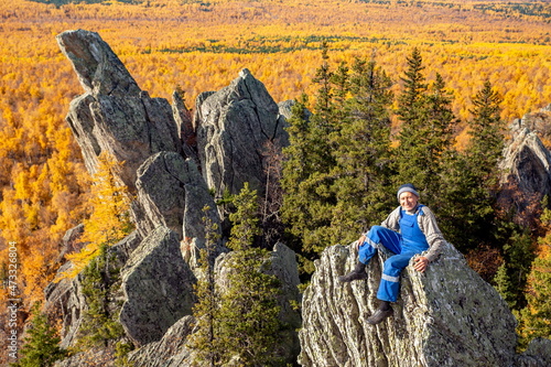 mature tourist posing on the rocks of the mountain round hill on the Alabiya ridge in the Ural mountains on an autumn sunny day. photo