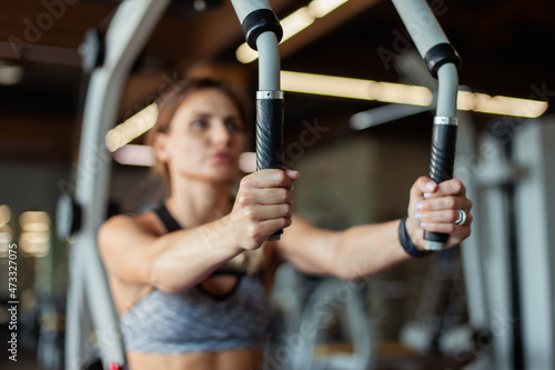 Beautiful fit woman in sportswear trains pectoral muscles in an exercise machine. Healthy lifestyle. Strong body