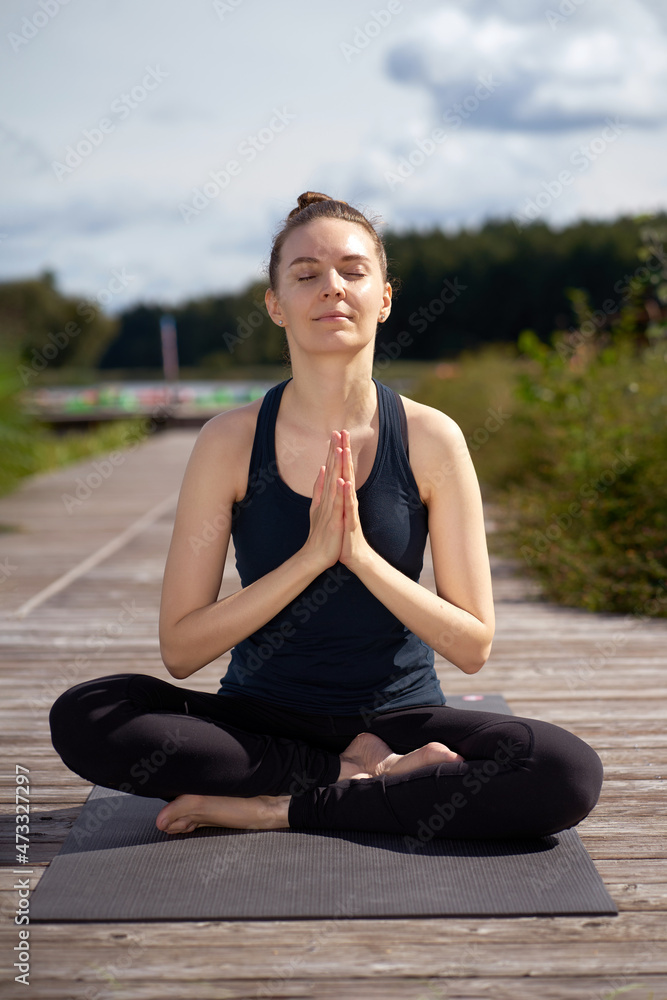 Young relaxing happy woman with closed eyes meditating on the wooden pier near lake. Young relaxing happy woman with closed eyes meditating on the wooden pier near lake.
