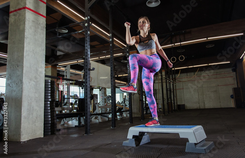 Young fit woman pulls on a stepper in the gym. Aerobics, fitness concept photo