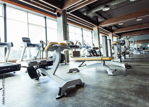 Modern gym interior with fitness equipment and exercise machines. Sports hall with large windows