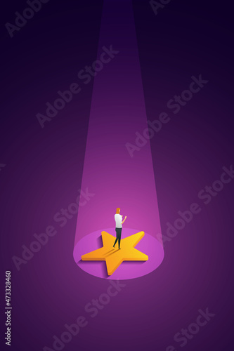 Businesswoman stands on a huge star with spotlights shining down on it.