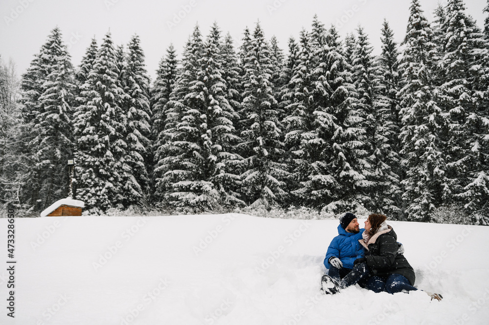 Walk in winter. Embracing couple enjoying snowfall. Man and woman having fun in the frosty forest. Romantic date in winter time.Christmas mood of a young family.  Love and leisure concept