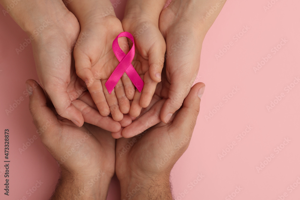 Family holding pink ribbon on color background, top view. Breast cancer awareness Family holding pink ribbon on color background, top view. Breast cancer awareness