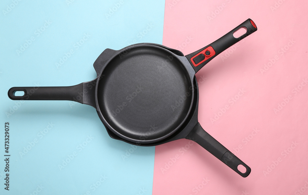 Stack of frying pans on pink blue background. Top view Stack of frying pans on pink blue background. Top view