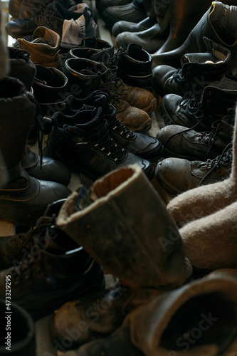 Many old work boots stand together. Old worn construction boots of workers. Background. Real scene. Shift shoes.