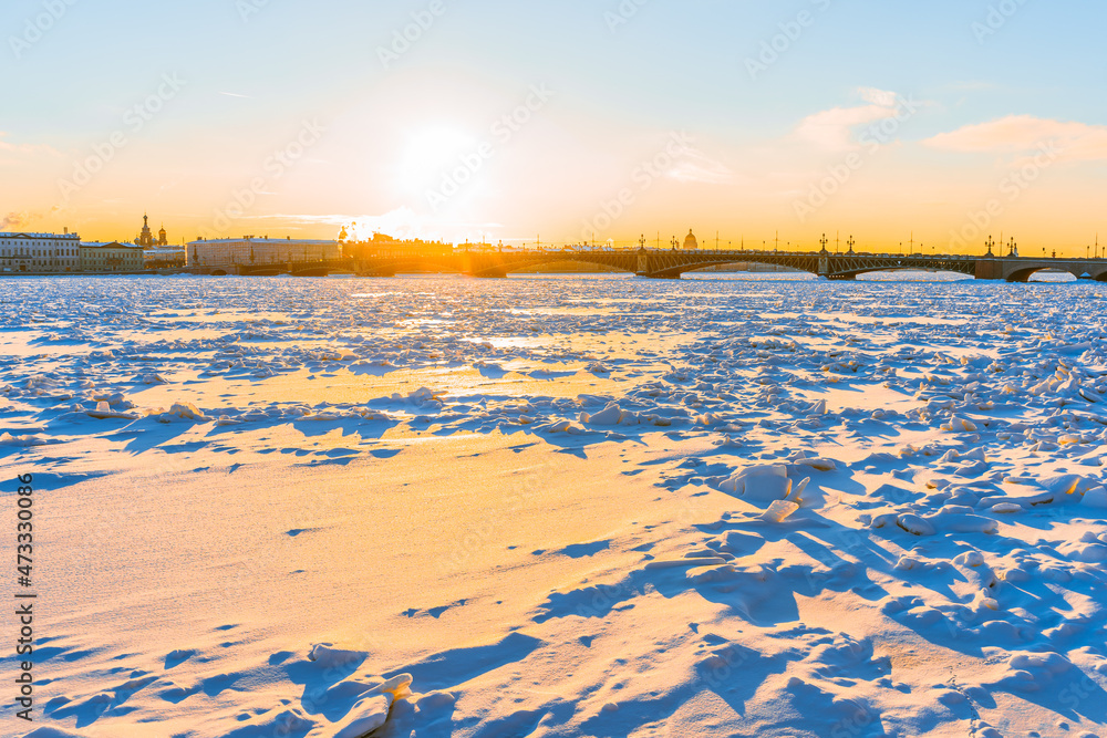 The embankment of Saint Petersburg in winter at sunset. The Neva River is covered with snow