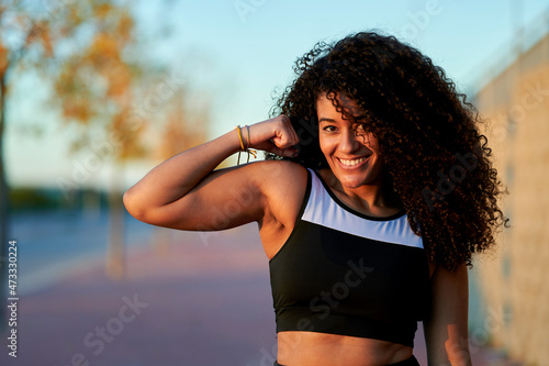 Smiling sportswoman flexing muscles at sunset photo
