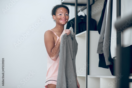 A young woman standing near her wardrobe and thinking what to wear