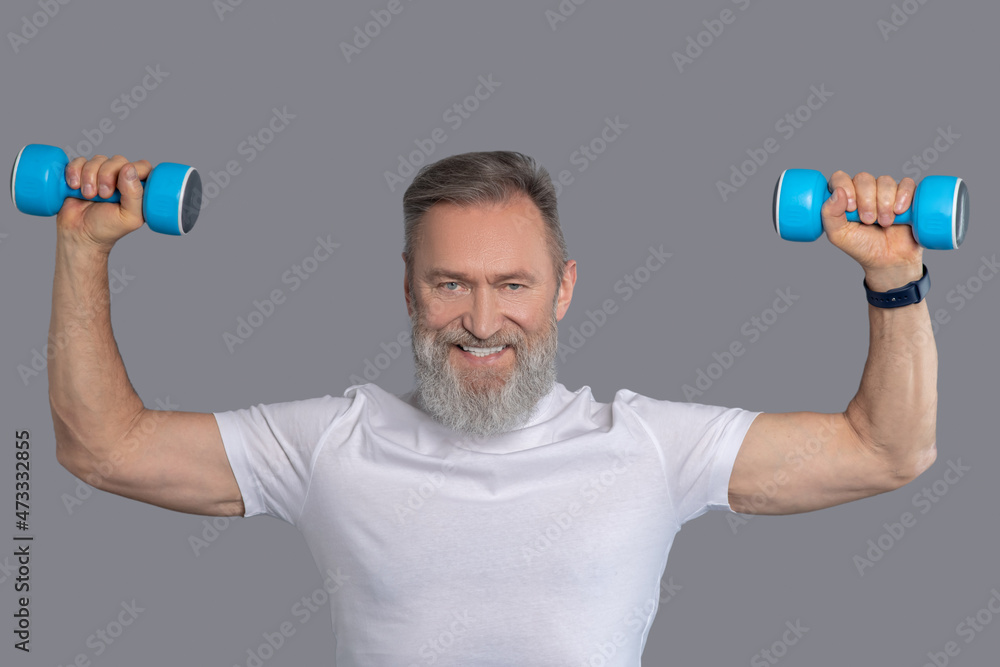 Smiling man with dumbbells having workout Smiling man with dumbbells having workout