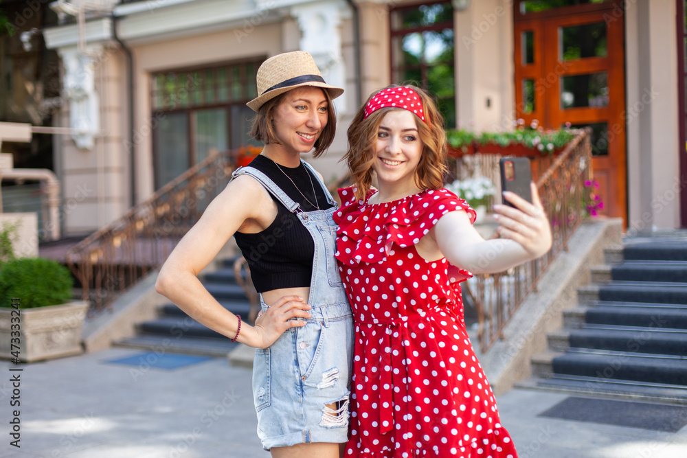 Naklejka premium Two attractive women friend make selfie on smartphone in city