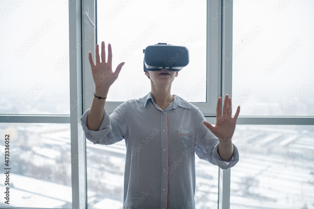 Woman in the VR glasses standing by a big window Woman in the VR glasses standing by a big window