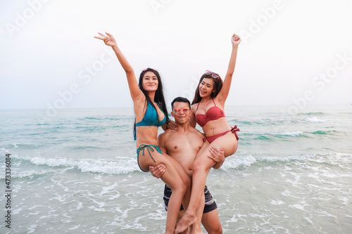 handsome man carry ladies wearing bikini in seaside on the beach