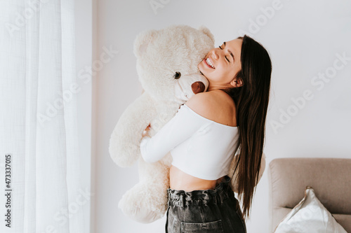 Young woman hugging teddy bear at home photo