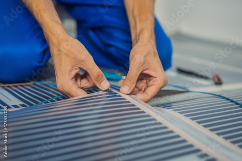 Master installs film warm floor in the room. Floor heating installation