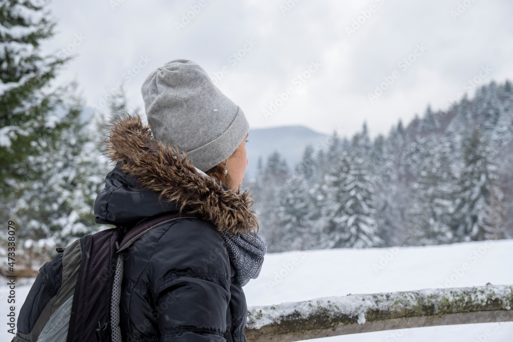 Caucasian woman in winter forest. Girl enjoys the snow falls. Young girl drinking tea in the forest during a snowfall.Have a good time outdoor in a snowy forest. Attractive young woman in forest