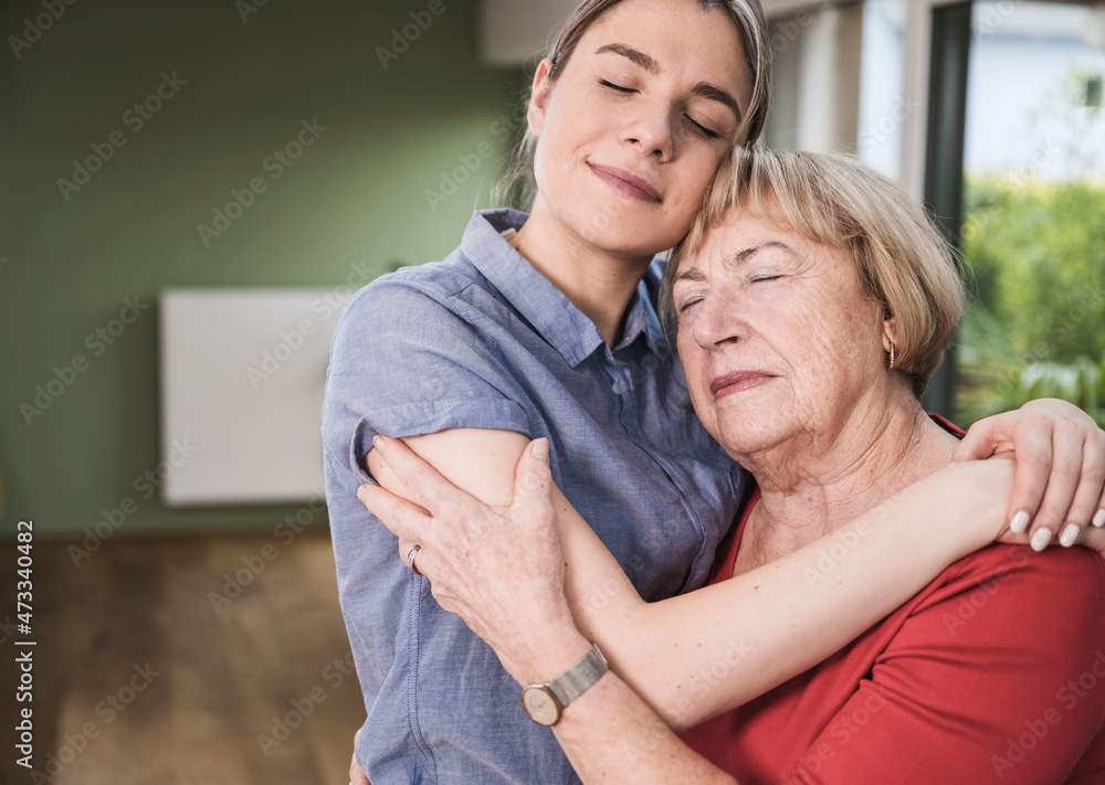 Women with eyes closed hugging each other at home Women with eyes closed hugging each other at home
