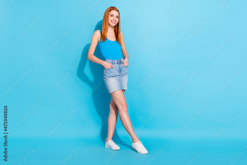 Photo portrait red haired woman in pretty singlet jeans skirt good mood isolated pastel blue color background Photo portrait red haired woman in pretty singlet jeans skirt good mood isolated pastel blue color background