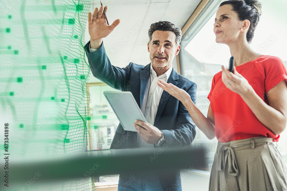 © Westend61 - Businessman discussing with colleague over futuristic business strategy at office © Westend61 - Businessman discussing with colleague over futuristic business strategy at office