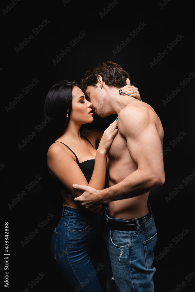 side view of sexy young couple hugging while kissing isolated on black. side view of sexy young couple hugging while kissing isolated on black.
