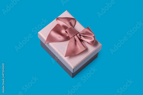 One gift box with a pink bow on a  blue  background, close up photo