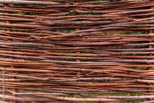 Close-up fence made of wooden rods. Wicker fence made of twigs. Natural fence made of branches. Background Texture