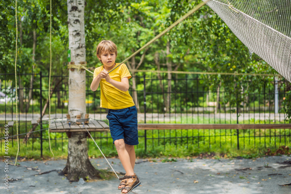 Little boy in a rope park. Active physical recreation of the child in the fresh air in the park. Training for children Little boy in a rope park. Active physical recreation of the child in the fresh air in the park. Training for children