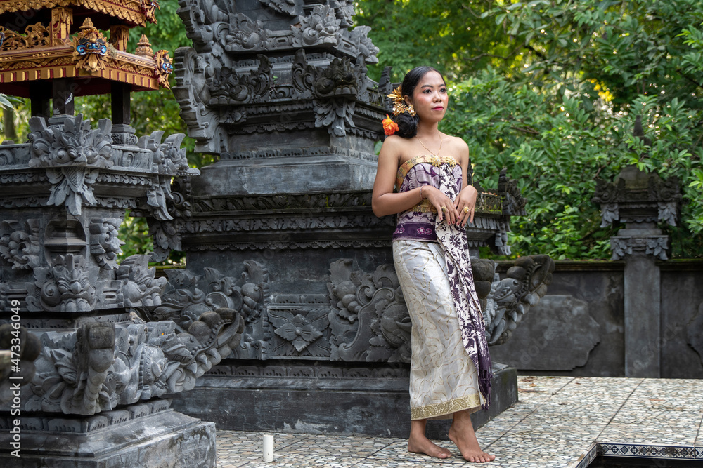 Balinese girl in a Hindu temple in Bali with incense sticks dressed in traditional dress. 