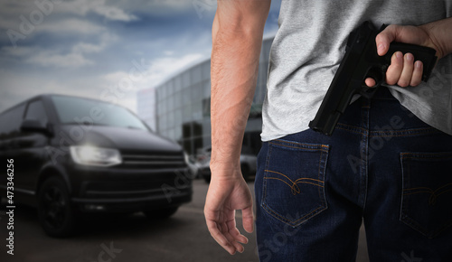 Man with gun near car outdoors, closeup