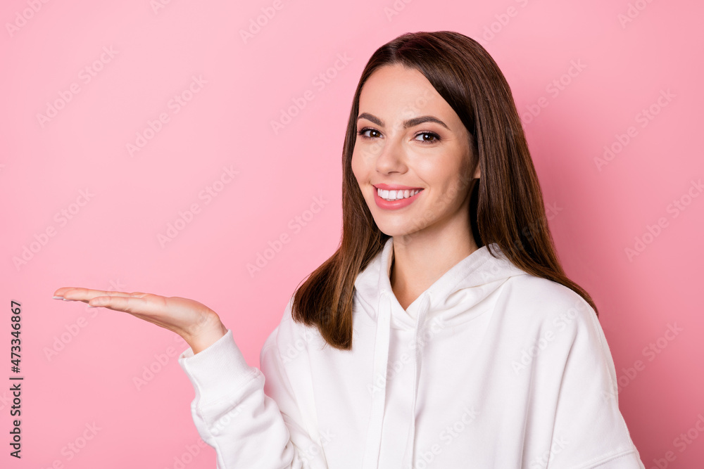 Photo of cheerful happy pretty young woman hold hand empty space good mood isolated on pink color background Photo of cheerful happy pretty young woman hold hand empty space good mood isolated on pink color background