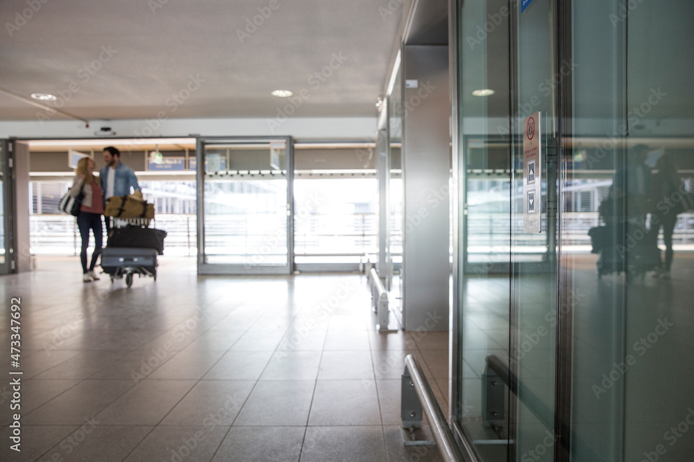 Young couple with luggage trolley at airport terminal Young couple with luggage trolley at airport terminal