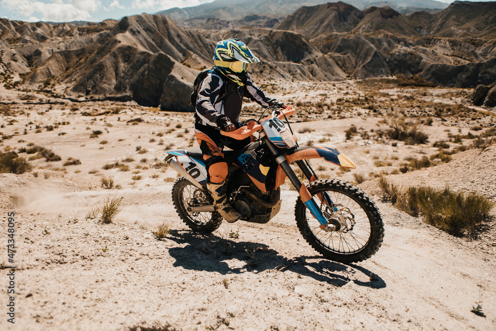 Male biker riding enduro motorcycle on desert road during sunny day Male biker riding enduro motorcycle on desert road during sunny day