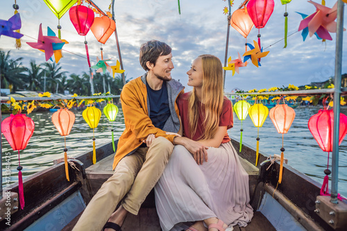 Happy couple of travelers ride a national boat on background of Hoi An ancient town, Vietnam. Vietnam opens to tourists again after quarantine Coronovirus COVID 19