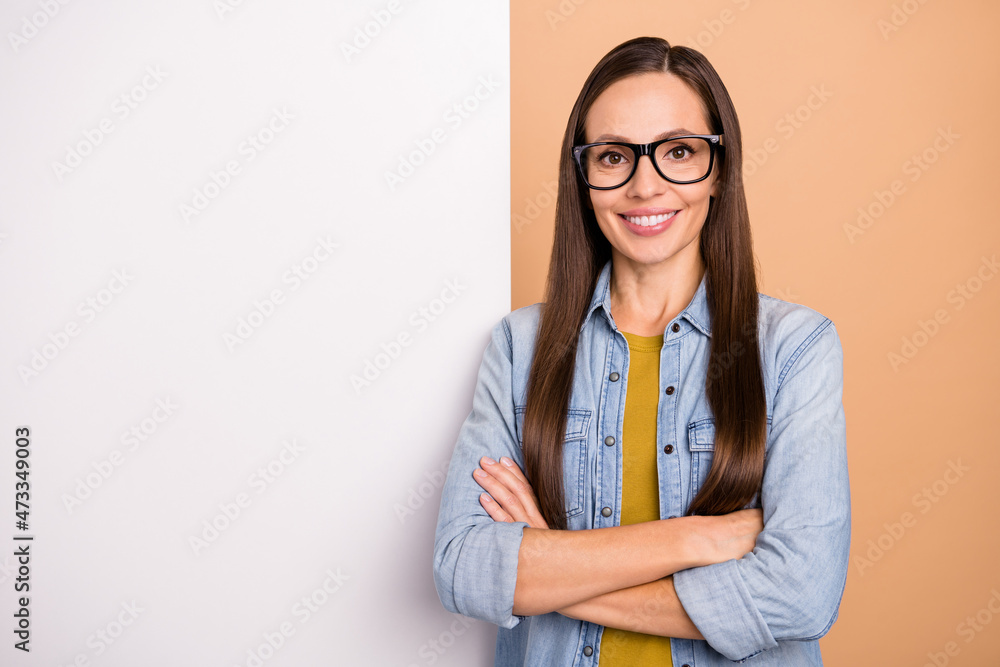 Photo of positive businesswoman crossed hands advertising product white billboard isolated on beige color background Photo of positive businesswoman crossed hands advertising product white billboard isolated on beige color background