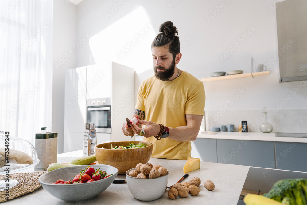 Man with beard cutting vegetable in kitchen Man with beard cutting vegetable in kitchen