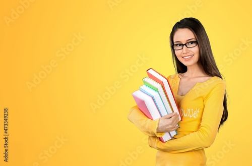 Smiling woman student with school books in hands on the background.