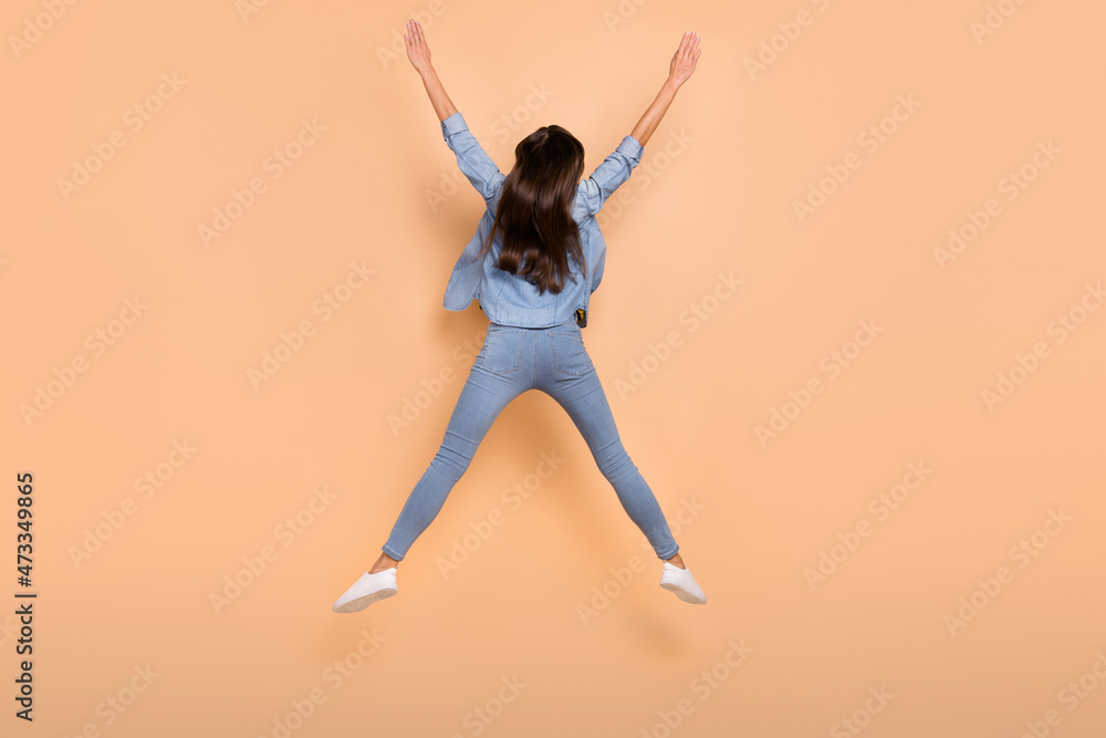 Full size photo of funky carefree girl jumping raise hands in victory personal improvement isolated on beige color background Full size photo of funky carefree girl jumping raise hands in victory personal improvement isolated on beige color background